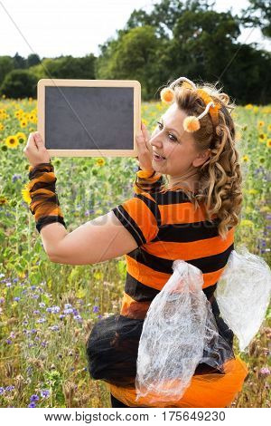 A woman dressed as a bee holds up a sign