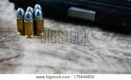 Bullets and a firearm on the wood. Bullets are a projectile expelled from the barrel of a firearm.