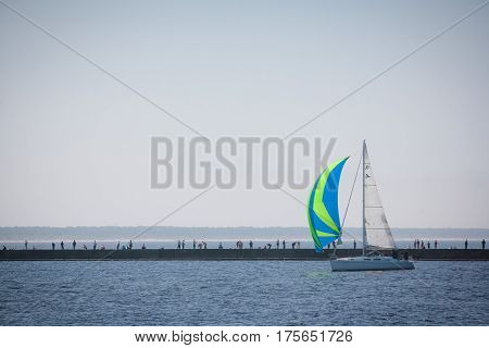 Anglers standing on the pier and sailing yacht