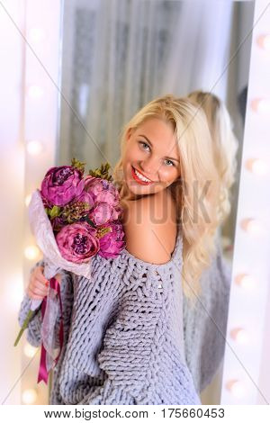 Amazing blonde holds a bouquet of peonies in her hands