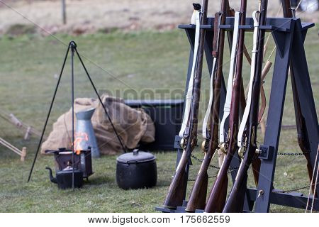 Reproduction vintage muskets at a military camp fire. Napoleonic war reenactment musket rifles. Selective focus on foreground.