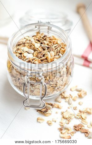 Top view breakfast of homemade granola cereal with nuts and fruit, honey with drizzlier, towel on white background. Healthy food, Diet, Detox, Clean Eating, Vegetarian concept.