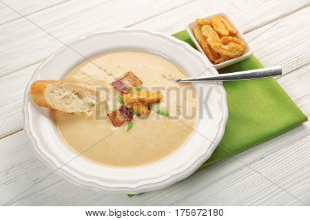 Delicious beer cheese soup with croutons and fried bacon on table