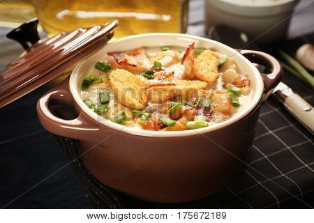 Delicious beer cheese soup with croutons and fried bacon on table