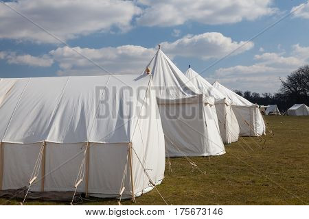 aNapoleonic war white military camping tents pitched on the open fields of English countryside. A battlefield reenactment site.