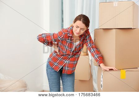 Young woman suffering from pain after moving heavy box