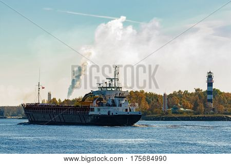 Black cargo ship with long reach excavator moving by Baltic sea