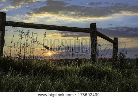 Setting sun as seen through a brace for a high tensile wire fence in rural Ohio