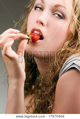 Mujer comiendo fresa rodando sus ojos con placer
