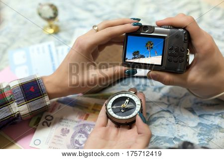 Travel Memories and Dreams Mood Composition Young Couple scrolling images on portable Camera from recent Journey topographic Map Compass foreign Cash Notes and other touristic items.