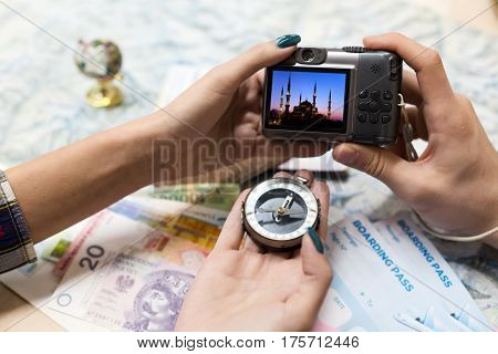 Travel Memories and Dreams Mood Composition Young Couple scrolling images on portable Camera from recent Journey topographic Map Compass foreign Cash Notes and other touristic items.