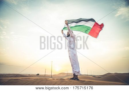 Arabian man walking in the desert at sunrise