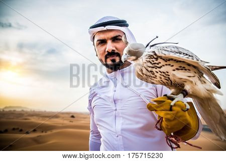 Arabian man walking in the desert at sunrise