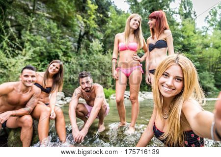 Group of friends having fun at waterfalls in the nature - People sunbathing at a river during summertime vacation