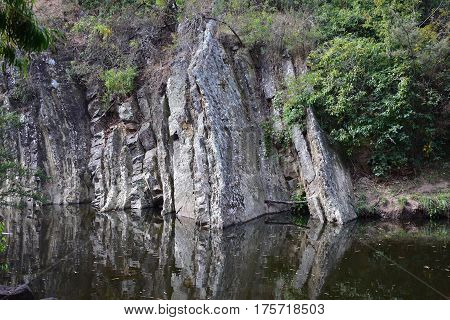 gorge with rock face going into water and reflection of cliff in water