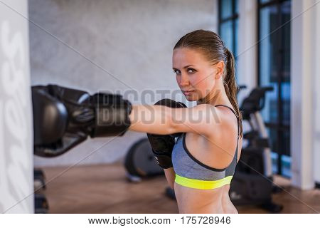 Young woman exercising in the gym on punching bag.
