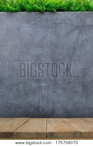 Wooden table with concrete wall or marble wall and ornamental plants or ivy or garden tree for background.