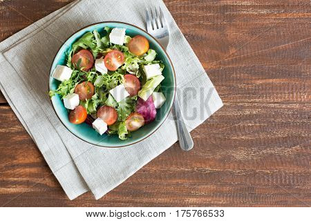 Salad with cherry tomatoes, Radicchio lettuce, frize, arugula and feta on wooden table
