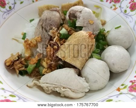 Hearty eating meal noodle with fish ball fishcake slices and boiled pork for light breakfast or lunch focus on foreground with blur background Fish ball noodle bowl in restaurant