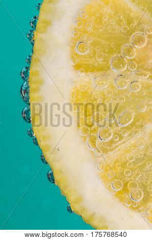 lemon slice in bubble soda on aquamarine background