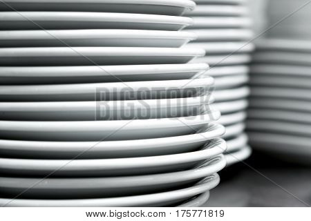 A lot of white plates on a white background, stacked evenly on each other