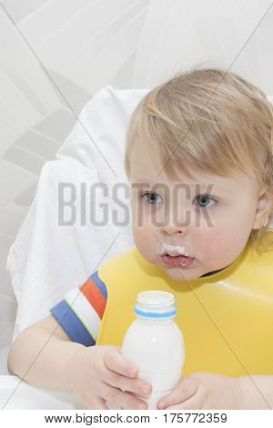 little boy is drinking milk. holding glass of milk.