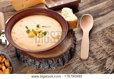 Delicious beer cheese soup with onion on table
