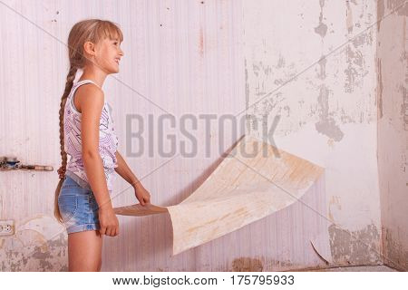 girl remove old wallpapers from the wall