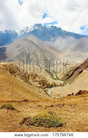 Gorge in the Himalayan mountains in the background of snowy peaks and blue sky with clouds. Nepal. Kingdom "Upper Mustang"