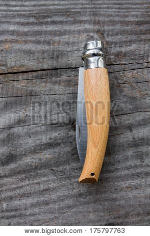 Pocket knife folded. Wood background. Knife with a unique mechanism.