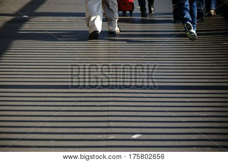 Bridge railings throws symmetrical and striped shadows on a walkway.