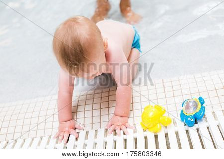 Baby playing in the water at indoor wsimming pool.
