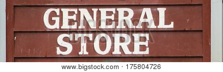 Old style General store sign on rustic brown clapboard wall.