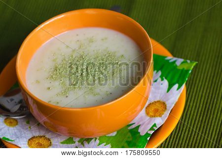 cream soup with grated green cheese in orange bowl