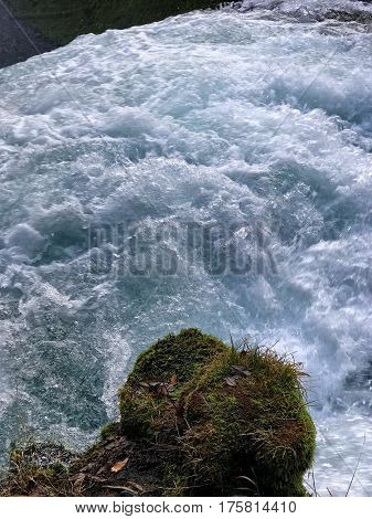 The white water's of the McKenzie River as it goes over Sahalie Falls in Western Oregon with a moss covered rock on the banks on a winter day.