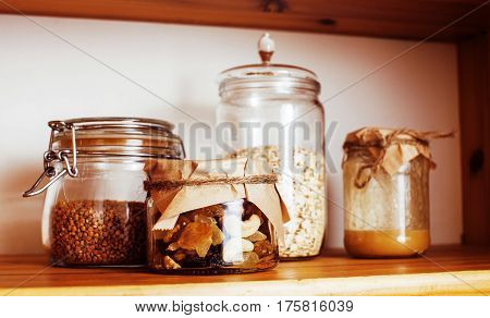 real comfort wooden kitchen with breakfast ingredients close up in glass, honey, oatmeal, milk, muesli
