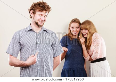 Young women friends talking gossiping about man. Two women whispering sharing secret news.