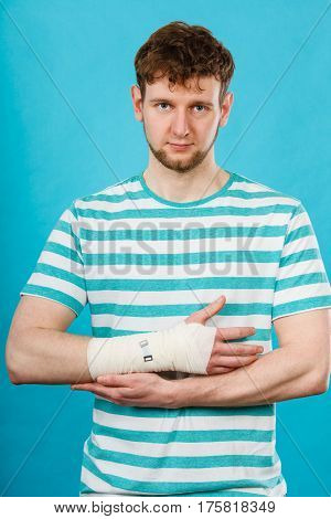 Fractures and dislocations concept. Man with hand in bandage. Helpful medication for painful palm arm of young guy.