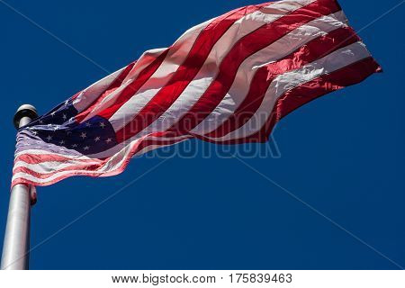 A U.S. flag unfurls from flagpole as wind blows.