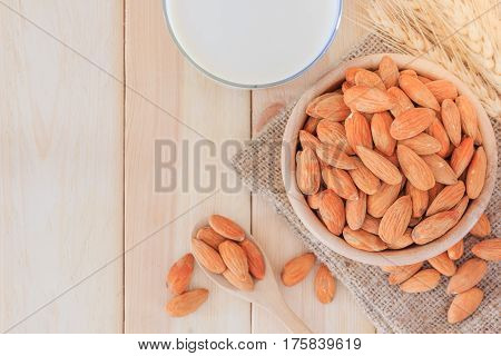 Almond milk in glass with almonds on wooden table Top view with copy space and text.