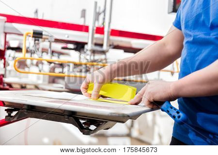 Man preparing material for screen printing in a workshop. Serigraphy industry. Manufacture work.