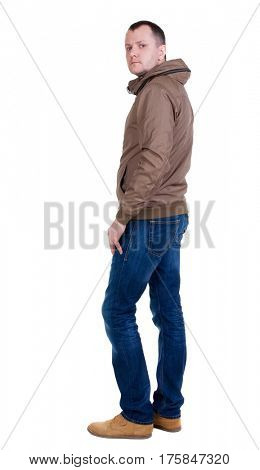Back view of handsome man in brown windcheater looking up.   Standing young guy in jeans. Rear view people collection.  backside view of person.  Isolated over white background.