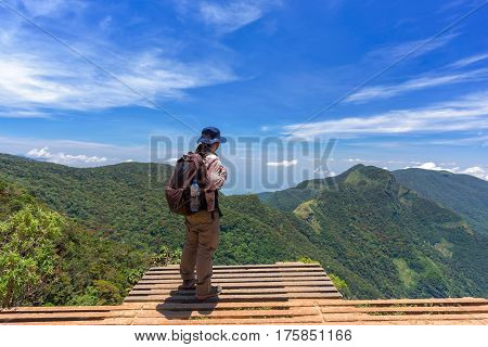 Man with hiking equipment walking in World's End within the Horton Plains National Park in Sri Lanka - success concept