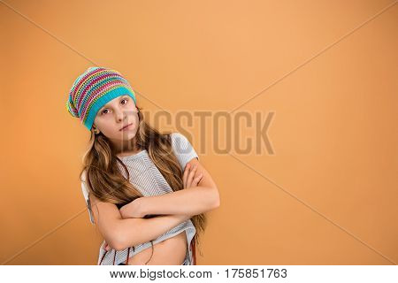 The face of sad teen girl in hat on brown studio background