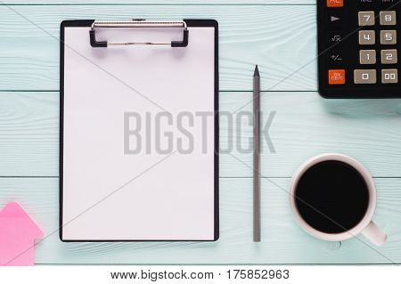 Folder clipboard with white blank paper sheet pencil cup of coffee and calculator with copy space top view. Business concept. Blank clipboard on wooden background flat lay.