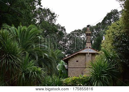 old gardener's 1800s brown brick house in botanic gardens with green ferns