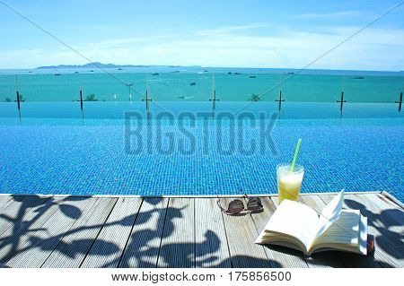 relax cocktail book sun glass at swimming pool with island view