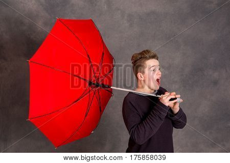 Teenager With Red Umbrella Standing In Strong Breeze