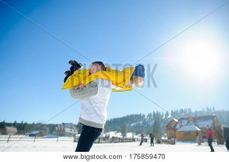 Young man holding in his arms his girlfriend. Man sturdily built easily picks up a fragile girl. Young people having fun. Against the background of the blue sky.