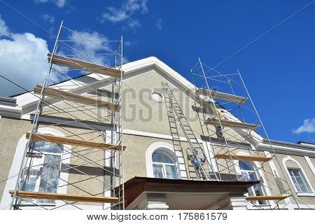 KYIV UKRAINE - March 22 2017: Painting and Plastering Exterior House Scaffolding Wall. Home Facade Insulation Sctucco and Painting Works During Exterior Wall Renovations and Repair. Builder Worker Plastering House Facade Outdoor
